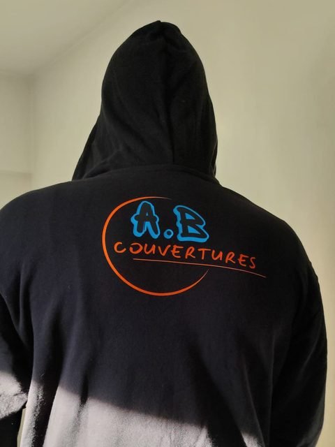 Sweat à capuche noir marqué d'un grand logo deux couleurs au dos, réalisé à l'atelier